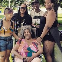Four young black women posing behind an older black woman in a chair