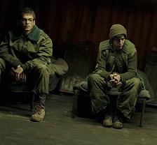 Two young white men in military uniforms sitting dejectedly on a bench