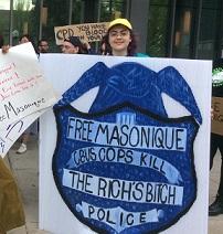 Woman holding a huge sign with a police badge that says Free Masonique Cbus Cops Kill 