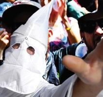 Klan member in pointy white mask holding his hand in the air