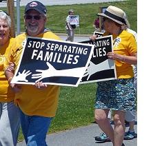 Older white people in yellow shirts holding signs that say Stop Separating Families