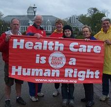 People holding a red sign that says Health Care is a Human Right 