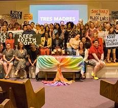 Many people posing inside a church with colorful banners and sign  about Keep Edith Home
