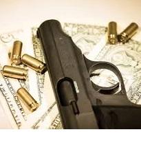 Dark gray handgun lying sideways on a table with gold bullets strewn around it