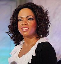 Photo of black woman with shoulder length black curly hair wearing a black top with white collar smiling at the camera