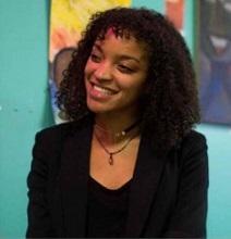 Young black woman smiling in a black suit against a colorful background