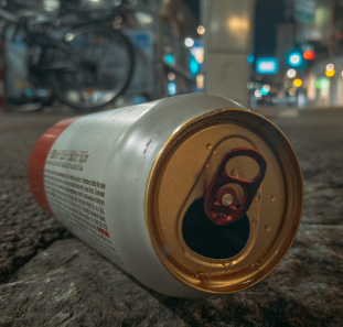Empty beer can on the ground outside at night