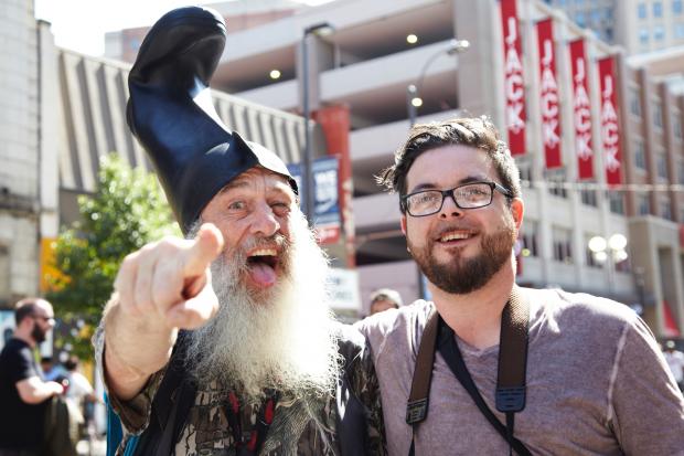Guy with white beard and funny hat standing next to young man with glasses