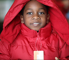 Young black child smiling and wearing a red winter coat with a hood