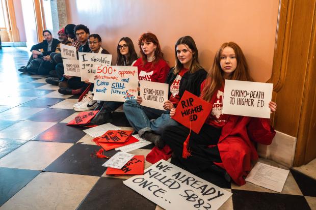 Students with protest signs sitting in a hall