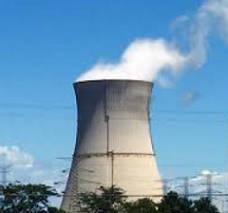 Big nuclear power plant smokestack with white smoke billowing out