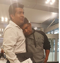 Two Latino men, one hugging the other, looking very sad