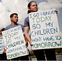 Two Latino people holding signs saying I go hungry so my children won't have to tomorrow