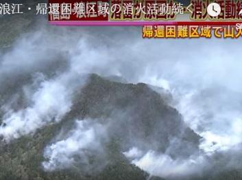 Looking down from sky at lots of smoke on ground with mountains and Japanese writing