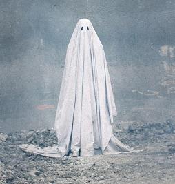 Person in a white sheet with two eye holes against an eerie gray background