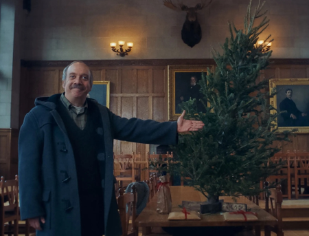 Older white man gesturing toward a decorated Christmas tree