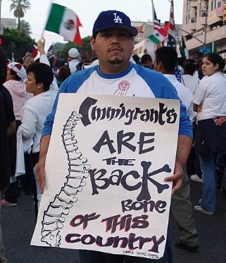 Man holding sign saying Immigrants are the Backbone of this country