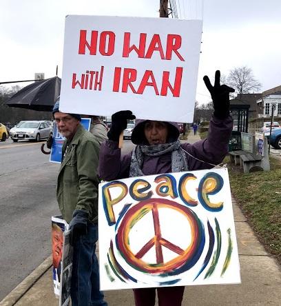 Woman holding No War with Iran and Peace protest signs
