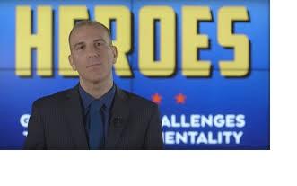 White balding guy against blue background with yellow words saying Heroes