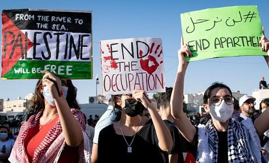 From left to right, protest signs read: "From the river to the sea Palestine will be free", "End the occupation", "End apartheid."