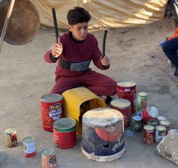 Young boy playing on homemade drums