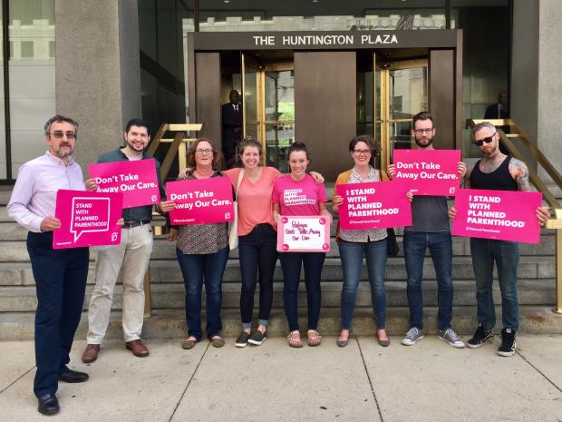 People with pink signs standing outside a government building