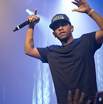 Black male rapper on stage with arms in air holding a mic