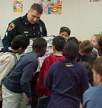 Man in police uniform surrounded by lots of small children