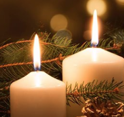 Two candles with close up on flames and pine branches in background