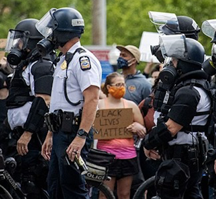 Cops and one small woman holding a BLM sign