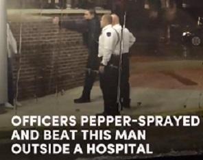 Photo of three white policemen outside one spraying pepper spray at a black man