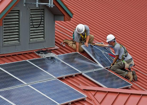 Men installiing solar panels on a roof