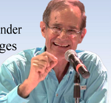 Older balding white man smiling and talking into a mic making a gesture with his hand