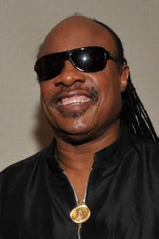 Smiling black man with big sunglasses and long braids in a black shirt