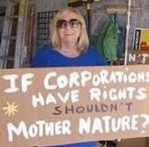 Blonde white woman with sunglasses holding a sign and smiling sign says If Corporations have rights shouldn't mother nature?