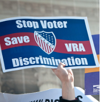 Red white and blue sign saying Stop Voter Discrimination Save VRA