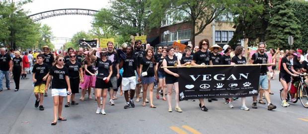 People in black and white Vegan shirts holding Vegan sign marching in parade
