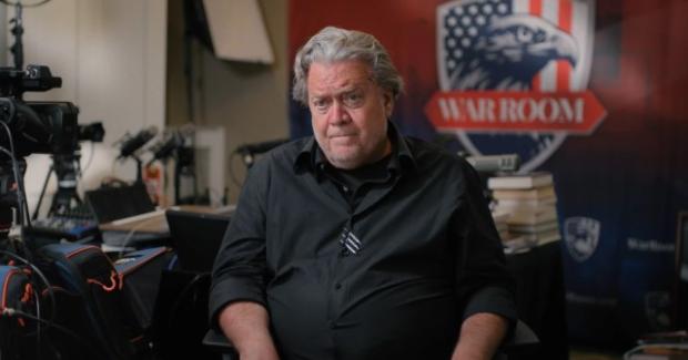 Gray haired white man by a sign reading War Room