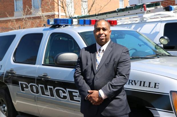 Black man standing next to police car