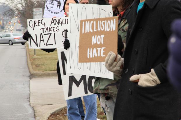People outside holding signs that say Inclusion Not Hate and Greg Anglin takes Nazi Money