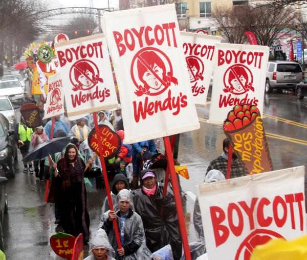People marching in the rain with Boycott Wendy's signs