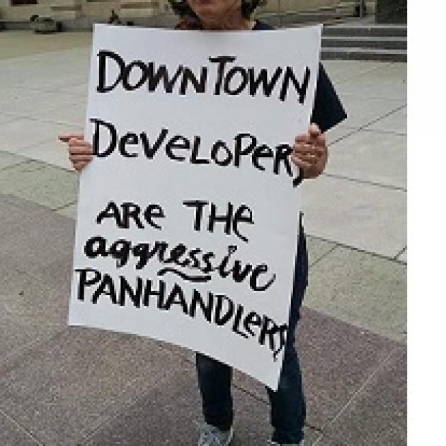 Sign being held outside reading Downtown developers are the aggressive panhandlers