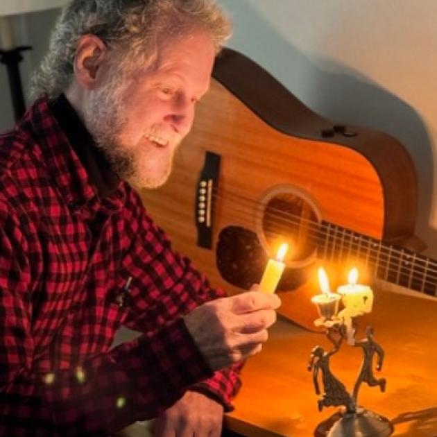 Bill Cohen with candle and guitar