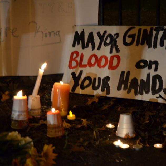 Candles and a sign that says "Mayor Ginther Blood on your hands"
