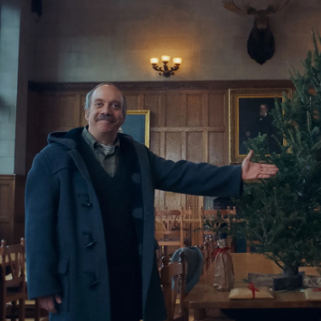 Older white man gesturing toward a decorated Christmas tree