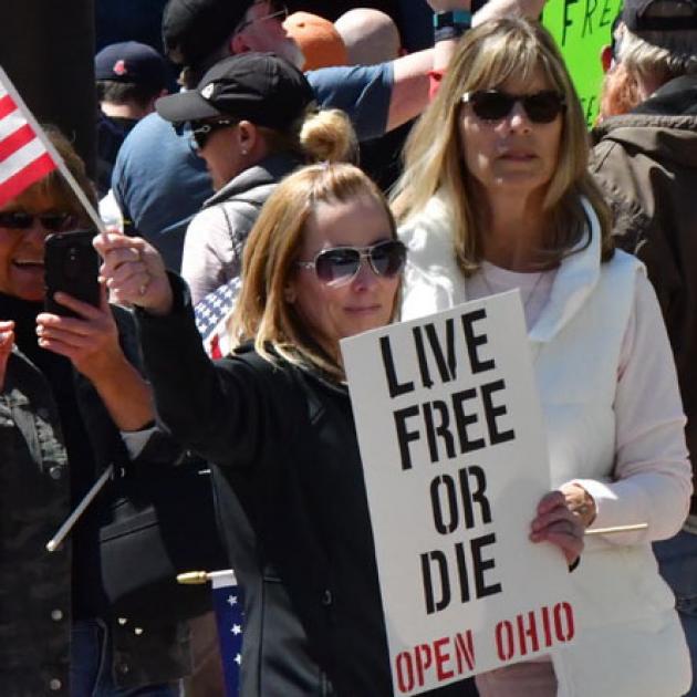 Woman holding sign saying Live Free or Die