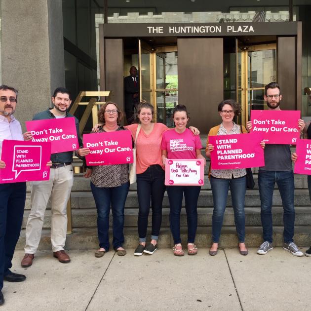People with pink signs standing outside a government building
