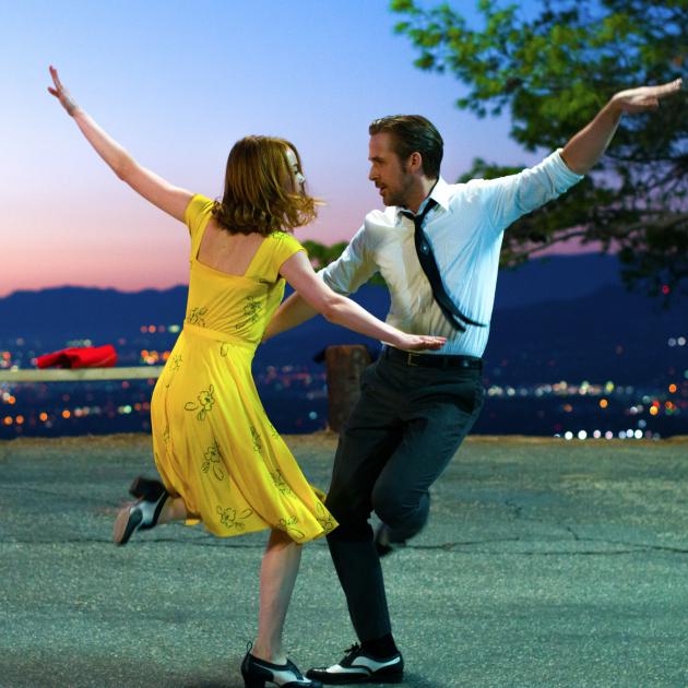 Woman in a yellow dress and man in a shirt and tie dancing wildly