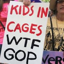 Woman holding sign saying Kids in Cages WTF GOP