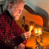 Bill Cohen with candle and guitar